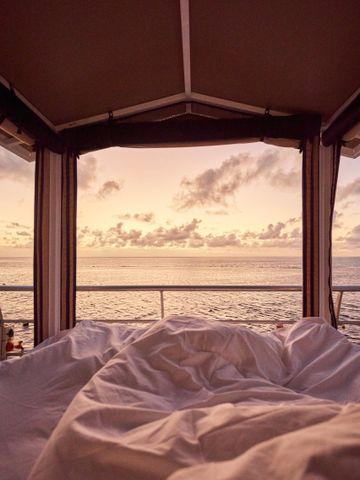 Blick vom Reefsleep-Bett unter dem Baldachin auf den Sonnenaufgang über dem Korallenmeer