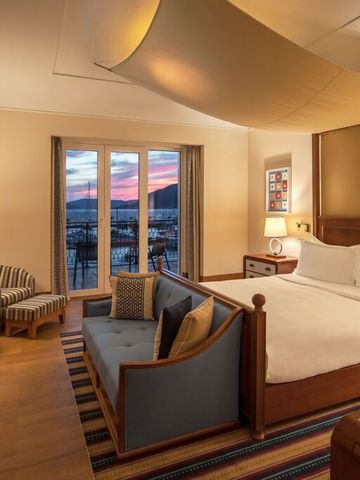 Luxussuite mit Kingsize-Bett und Meerblick im Abendlicht.