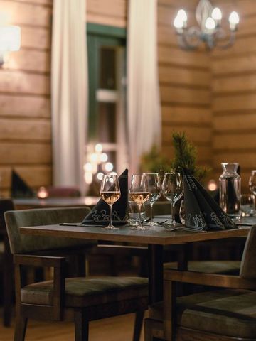 Gedeckte Tische im Restaurant des Haupthauses mit Holzwänden, Kronleuchter und Vorhängen