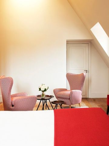 Elegant eingerichteter Sitzbereich mit roten Akzenten und Dachschrägen.