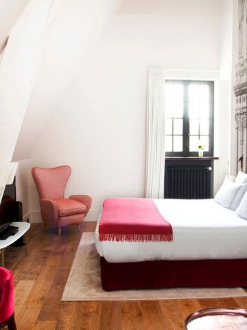 Helles Hotelzimmer mit Dachschräge und eleganter Einrichtung in Rot und Weiß