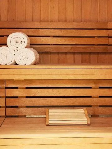 Saunaraum mit Holzbänken und gerollten Handtüchern