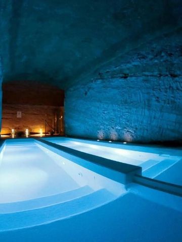 Beleuchteter Spa-Bereich mit schmalem, von Steinmauern umgebenem Pool.