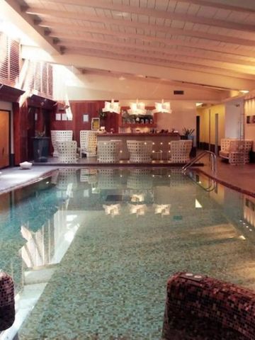 Indoor-Pool mit Mosaikfliesen und stilvollem Barbereich.