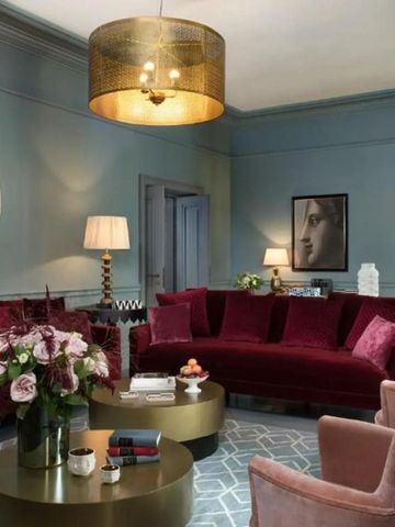 Elegantes Wohnzimmer mit weinrotem Sofa und luxuriöser Dekoration.