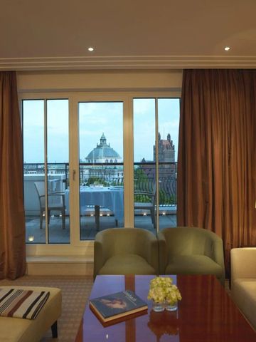 Hotelsuite mit Blick auf Terrasse und Stadtpanorama bei Abenddämmerung.