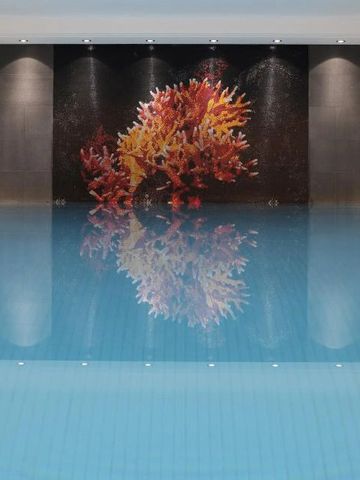 Beleuchtetes Hallenbad mit modernem Kunstwerk an der Wand