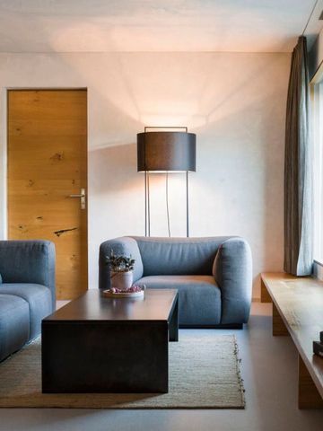 Helles Wohnzimmer mit modernen Sesseln, Couchtisch und großen Fenstern