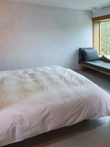 Moderner Hotelraum mit Doppelbett und Panoramafenster mit Waldblick