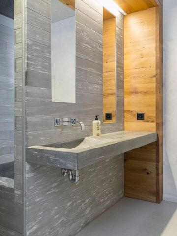 Badezimmer im Hotel mit Waschbecken, Spiegel und moderner Holz- und Fliesenverkleidung