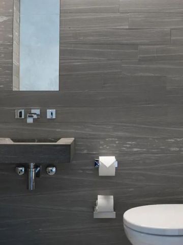 Hotel-WC mit modernen grauen Fliesen und schlichtem Design
