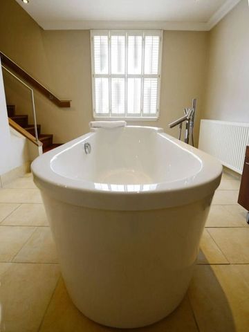 Moderne freistehende Badewanne in hellem Badezimmer mit Fenster