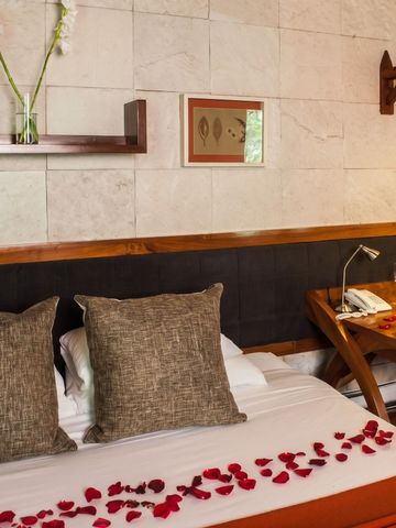 Einladendes Hotelzimmer mit Doppelbett und Rosenblättern dekoriert.