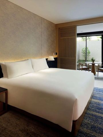 Modernes Hotelzimmer mit großem Bett und Blick auf den privaten Garten
