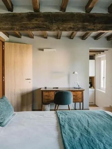 Einladendes Zimmer mit Holzbalkendecke und modernem Schreibtisch