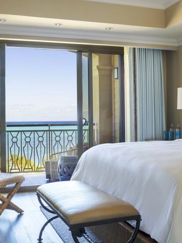 Helles Schlafzimmer mit Balkon und Meerblick im Hintergrund.