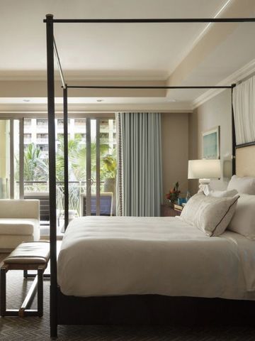 Elegantes Zimmer mit Himmelbett und Blick auf den Balkon mit Palmen