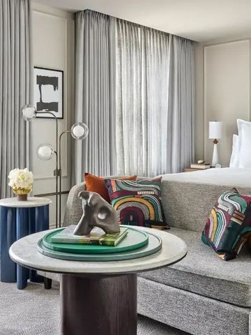 Helles Gästezimmer mit eleganter Sitzecke und modernen Kunstwerken