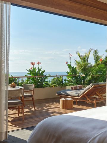 Terrasse mit Liegestühlen und üppiger Bepflanzung mit Meerblick