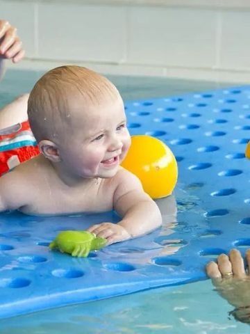 Lachendes Baby mit Schwimmspielzeug im Kinderbecken