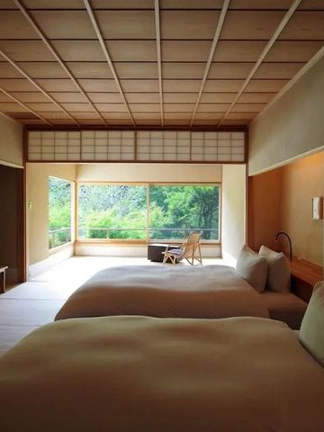 Geräumiges Zimmer mit zwei Betten, großen Fenstern und Blick auf einen grünen Garten.