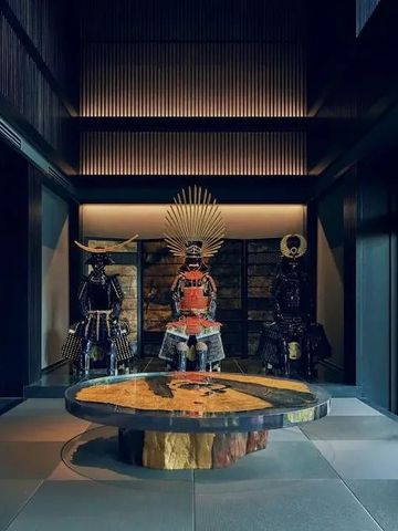 Stilvolle Hotelhalle mit traditionellen Rüstungen als Dekor und einem kunstvollen Tisch.