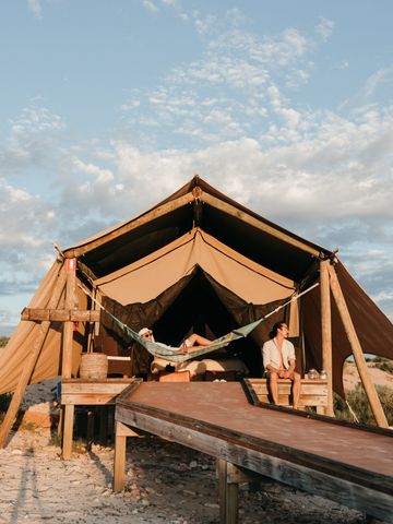 Safarizelt mit Holzdeck und Hängematte in den Dünen, Holzsteg führt zum Eingang