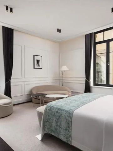 Geräumiges Hotelzimmer mit großem Bett, stilvollen Möbeln und Blick aus großen Fenstern