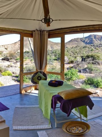 Wellnessraum mit Blick auf Berglandschaft und Massagetisch.