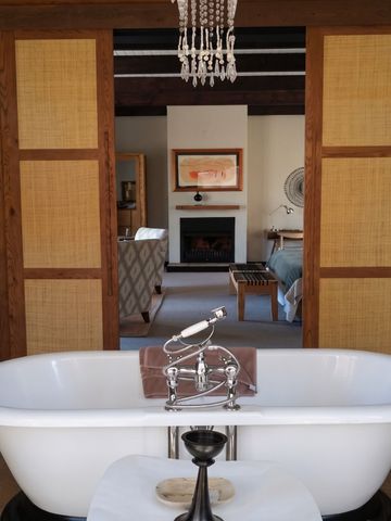 Luxuriöses Badezimmer mit freistehender Badewanne und Kamin im Hintergrund.