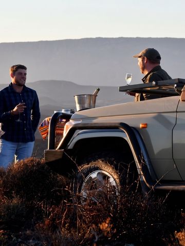 Safari-Erlebnis mit Geländewagen und Gästen in der südafrikanischen Landschaft.