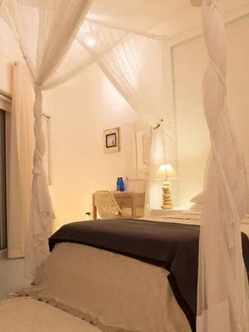 Schlafzimmer mit Himmelbett, dezenter Beleuchtung und eleganter Dekoration.