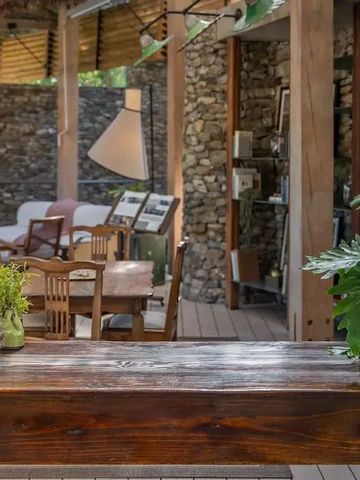 Gemütliche Outdoor-Lounge mit Steinwänden und Holzmöbeln im Grünen