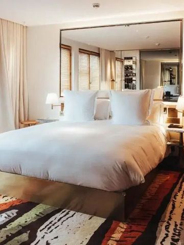 Helles Hotelzimmer mit King-Size-Bett und großen Fenstern