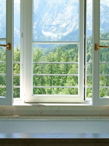 Badewanne mit offener Fensteransicht auf bewaldete Berge