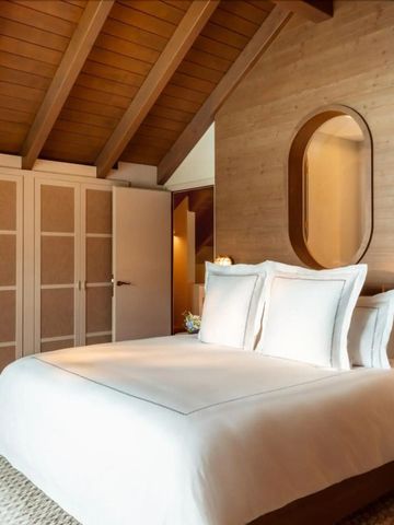 Gehobenes Dachzimmer mit Holzelementen und komfortablem Bett