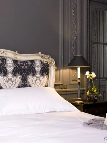 Luxuriöses Schlafzimmer mit dekorativem Kopfteil und klassischen Lampen