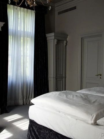 Helles Schlafzimmer mit großen Fenstern und luxuriösem Bett im Schlosshotel Berlin