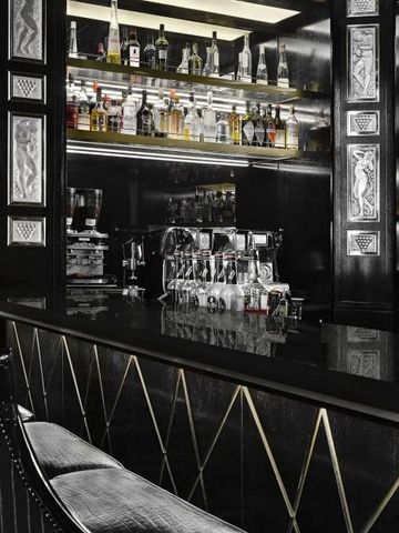 Elegante Hotelbar mit schwarzer Theke und Regalen voller Flaschen