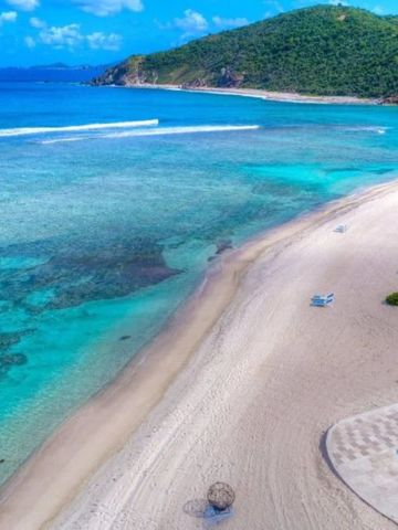 Weißer Sandstrand mit türkisfarbenem Wasser und sanften Wellen
