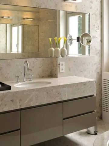 Luxuriöses Badezimmer aus Marmor mit großem Spiegel und Fenster