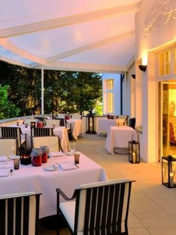 Elegante Terrasse eines Restaurants mit gedeckten Tischen bei Abenddämmerung