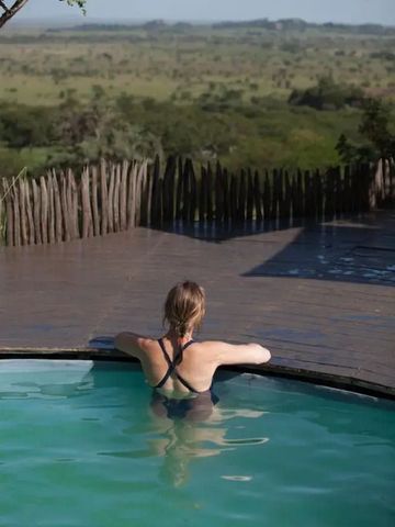 Frau entspannt im Pool mit Blick auf die Serengeti-Landschaft