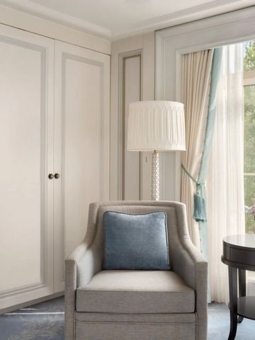 Hotelzimmer mit gemütlichem Sessel und grünem Gartenblick durch große Fenster.