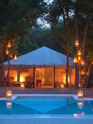 Stimmungsvoll beleuchtetes Zelt bei Nacht mit Pool im Vordergrund