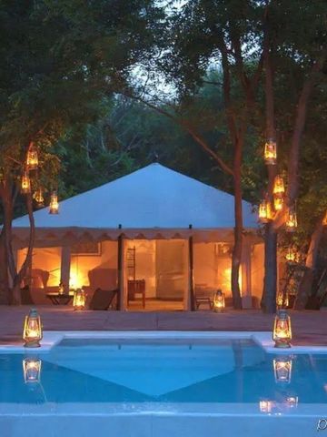 Beleuchtetes Safari-Zelt am Abend vor einem Pool
