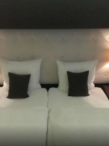 Gemütliches Doppelbett mit gepolstertem Kopfteil und Nachttischlampen