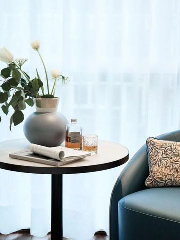 Moderner Beistelltisch mit Blumenstrauß, Glas und Zeitschrift in hellem Raum
