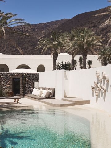 Ruhiger Poolbereich umgeben von Palmen und weißer Architektur