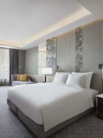 Geräumiges Hotelzimmer mit King-Size-Bett und großen Fenstern